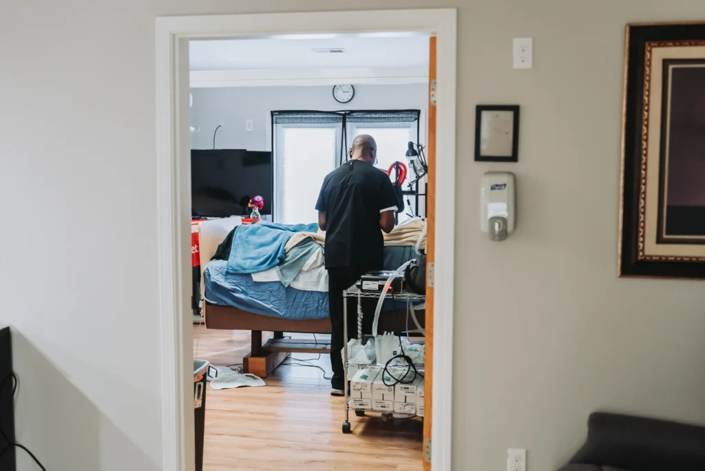 Caregiver assisting an elderly patient in a bedroom.