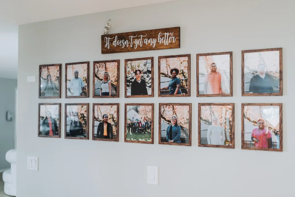 Family photo wall with multiple framed pictures and a wooden sign above.